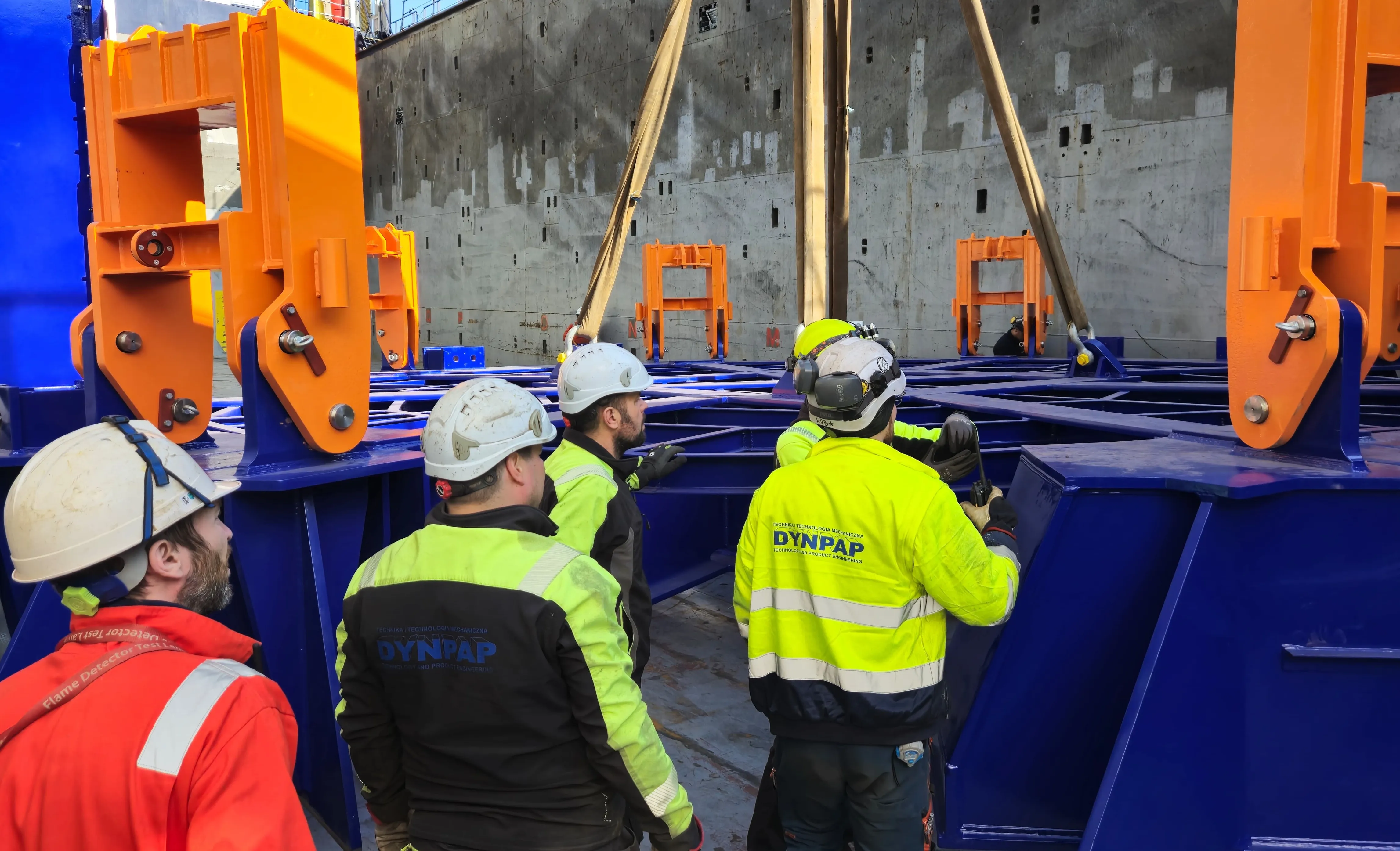 Pracownicy DYNPAP w kaskach i odzieży ochronnej podczas konsultacji ze specjalistą od BHP